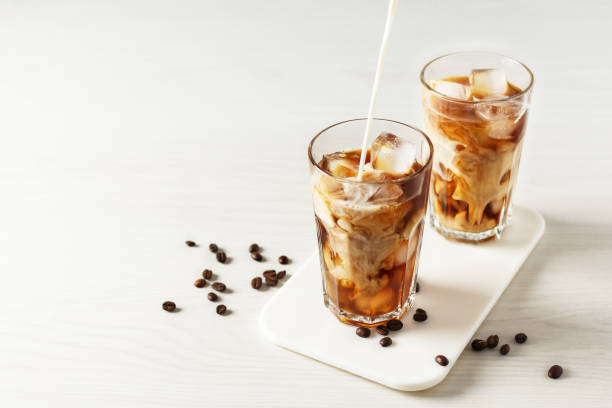 istock Pouring milk into glass with iced coffee. 1305319185