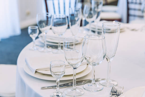 istock Fancy table set for dinner with napkin glasses in restaurant, luxury interior background. Wedding elegant banquet decoration and items for food arranged by catering service on white tablecloth table 1305320869