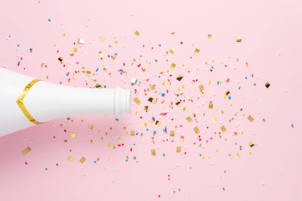 istock White champagne bottle with confetti on pink background. Minimal party concept. 1305322036