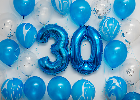 Blue number 30 celebration foil balloons with helium balloons on white background. Party decoration for happy birthday celebration.