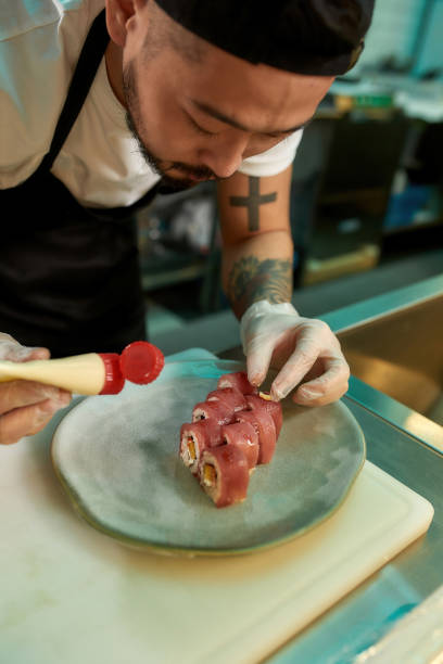 istock Professional sushi chef carefully adding final touch with dedication to his perfect tuna sushi 1305322350