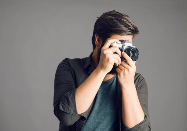 istock Portrait of a photographer using a retro camera over gray background 1305322389