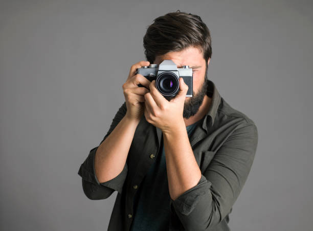 istock Portrait of a photographer using a retro camera over gray background 1305322448