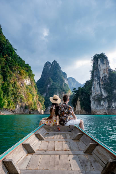 coppia in barca longtail che visita il parco nazionale di khao sok a phangnga in thailandia, parco nazionale khao sok con barca longtail per i viaggiatori, lago cheow lan, diga di ratchaphapha - tailandia foto e immagini stock