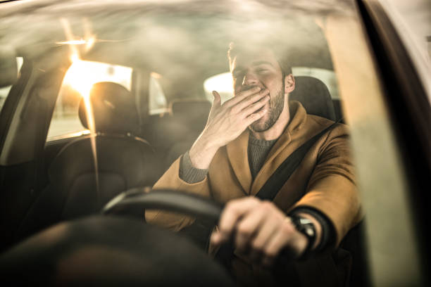 istock Tired man driving a car and yawning. 1305324810