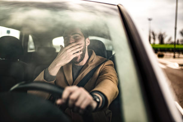istock Tired man driving a car and yawning. 1305324818