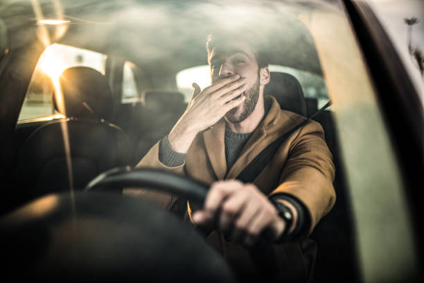 istock Tired man driving a car and yawning. 1305324830