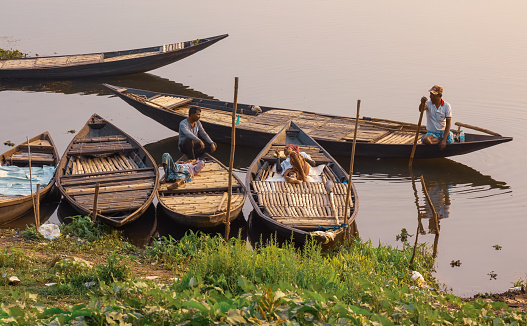 West Bengal, India, February 14,2021: Boatman with joined hands trying to pursue tourists for a boat ride at sunset in a village in Bardhaman district in West Bengal, India.