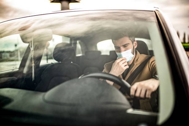 istock Man driving a car and wearing a face mask. 1305325931