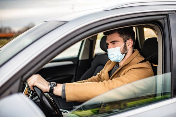 istock Man driving a car and wearing a face mask. 1305325949