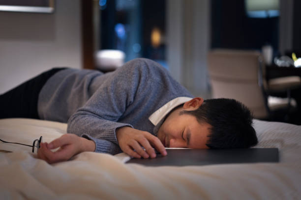 istock Asian man getting tired and sleeping while working on bed with laptop at night 1305327355