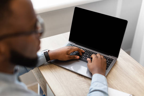 istock African Businessman Using Laptop With Blank Screen Sitting In Office 1305327521