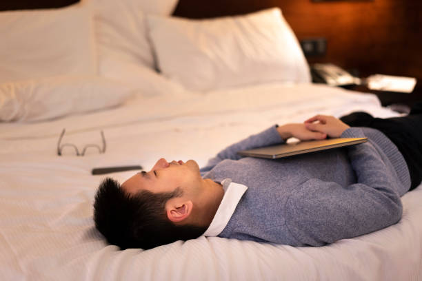 istock Asian man getting tired and sleeping while working on bed with laptop at night 1305327650