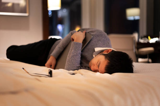 istock Asian man getting tired and sleeping while working on bed with laptop at night 1305327657