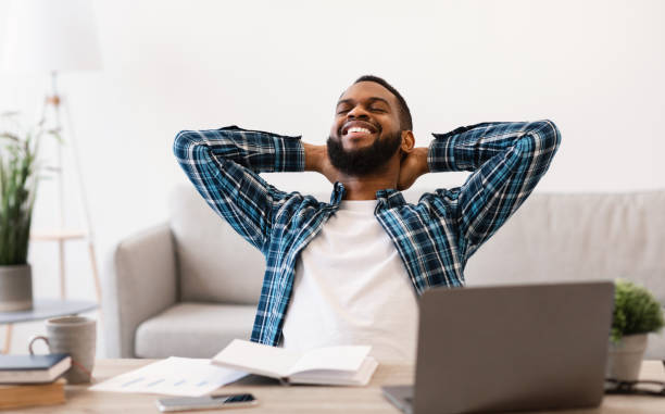 istock Black Businessman Sitting Holding Hands Behind Head Relaxing At Workplace 1305327699