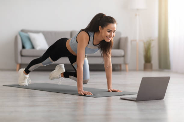 istock Active woman doing fitness at home, using laptop 1305329381