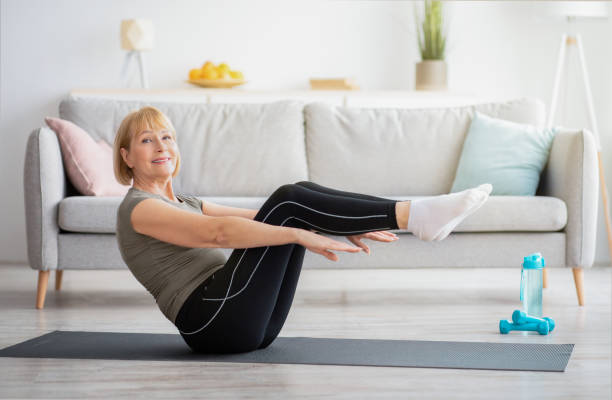 glückliche seniorin macht bauchmuskeln auf yogamatte zu hause. bleiben sie fit und gesund während der covid-quarantäne - core strength stock-fotos und bilder