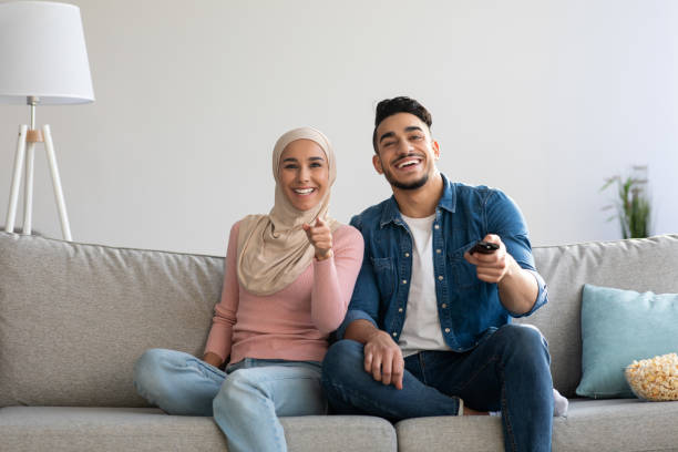 istock Joyful muslim couple watching funny TV programs 1305330192