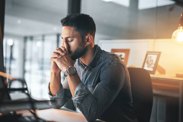 Ok, breathe! Cropped shot of a handsome young businessman feeling stressed while working in his office late at night managing stress stock pictures, royalty-free photos & images
