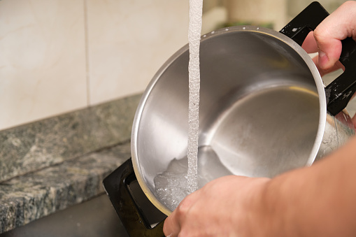 Cropped image of a man hands washing a pot or doing the dishes. Cleaning household chores.