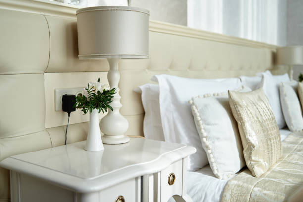 Hotel bedroom interior with double bed and bedside table, copy space. Large buttoned headboard of luxury bed, copy space. Chesterfield style checkered soft headboard