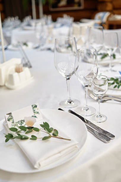istock Table setting with blank guest card on empty white plate and cutlery on table, copy space. Menu mockup, place setting at wedding reception. Table served for wedding banquet in restauran 1305332642
