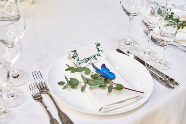 istock Table setting with blank guest card on empty white plate and cutlery on table, copy space. Menu mockup, place setting at wedding reception. Table served for wedding banquet in restauran 1305332655