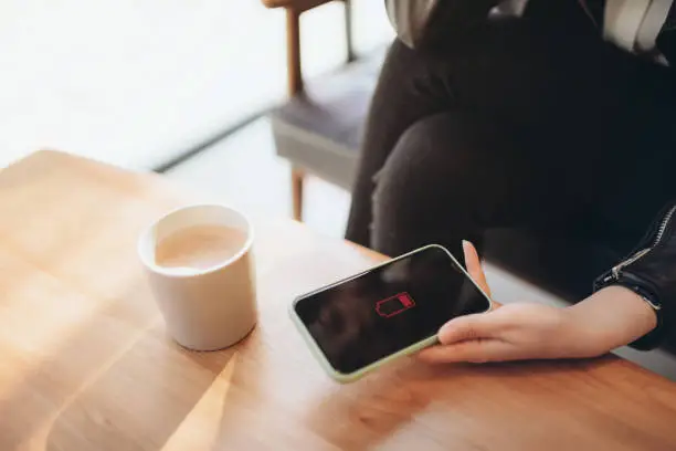 Woman holding a smartphone computer that needs charging