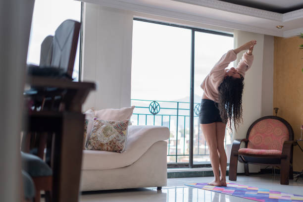 istock Woman performs her stretches and greets the sun before starting her yoga session from her living room 1305333821