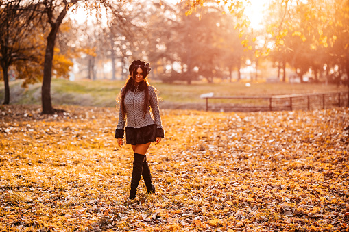 Elegant beautiful young woman walking in autumn public park wearing coat.