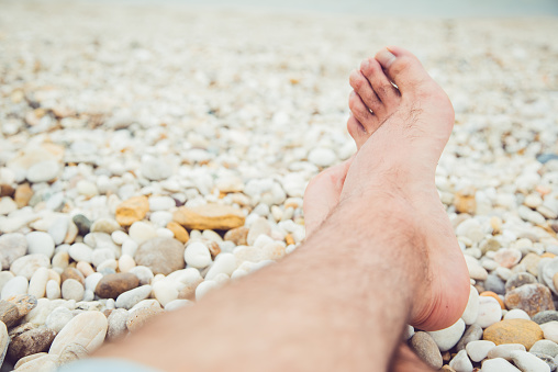 Male feet on a marble beach.