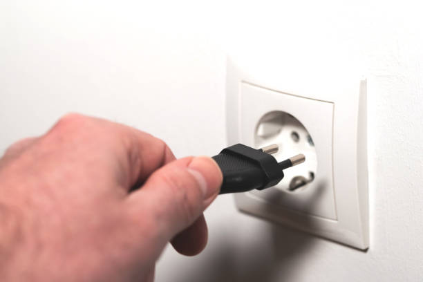 istock hand inserting power cord plug into wall outlet 1305336365