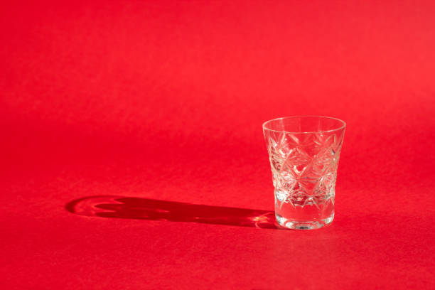 istock Beautiful crystal glasse with shadows on a bright red background, close-up 1305336640