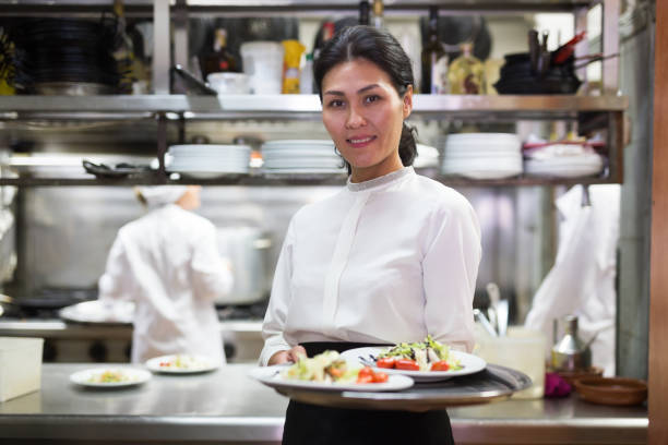 istock Confident waitress holding cooked meals in restaurant kitchen 1305338158