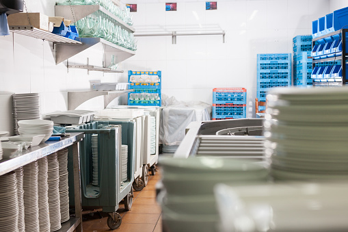 View of empty restaurant kitchen with storage racks full of clean tableware