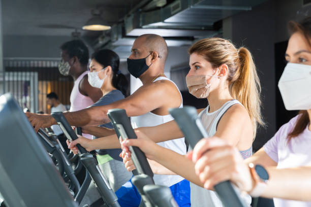 istock Active people in protective masks having running elliptical trainer class in club 1305339518