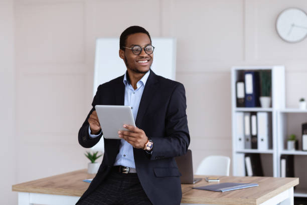 istock Joyful african american young businessman using digital tablet in office 1305342525