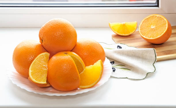 istock Oranges on a plate on the sill of the window. 1305342647