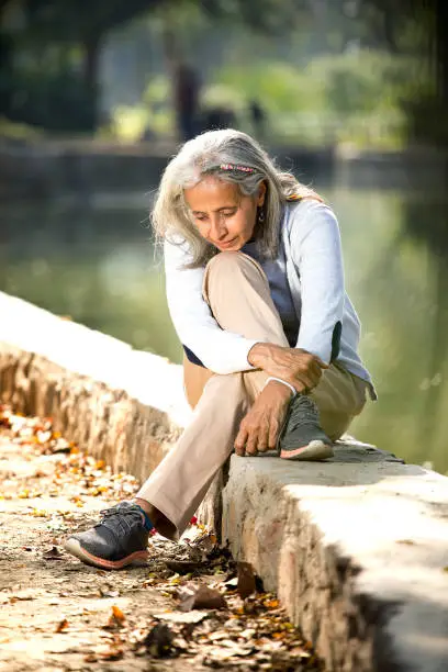 Thoughtful senior woman sitting alone at lakeshore