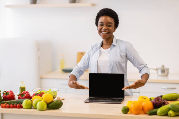 istock African Woman Showing Laptop Empty Screen Standing In Kitchen 1305342680