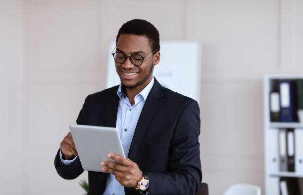 istock Positive black guy entrepreneur using digital tablet in office 1305342870