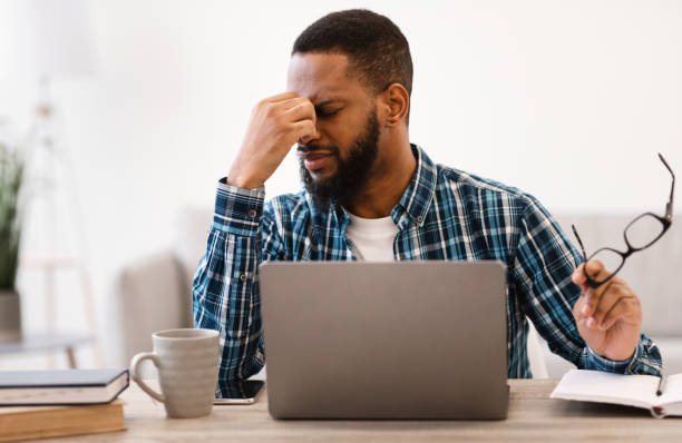 istock Black Guy Massaging Tired Eyes After Work On Laptop Indoor 1305344536