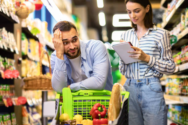 lustiges junges paar mit einkaufsliste im supermarkt - fear terrified shock humor stock-fotos und bilder