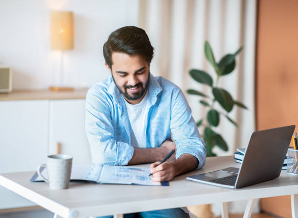 istock Smiling Arab Man Working With Documents And Laptop At Home Office 1305344694