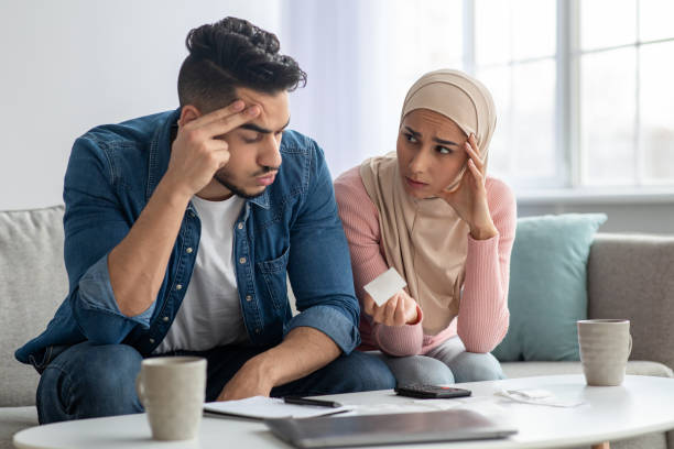 istock Confusded lady in hijab showing bill her upset husband 1305344779
