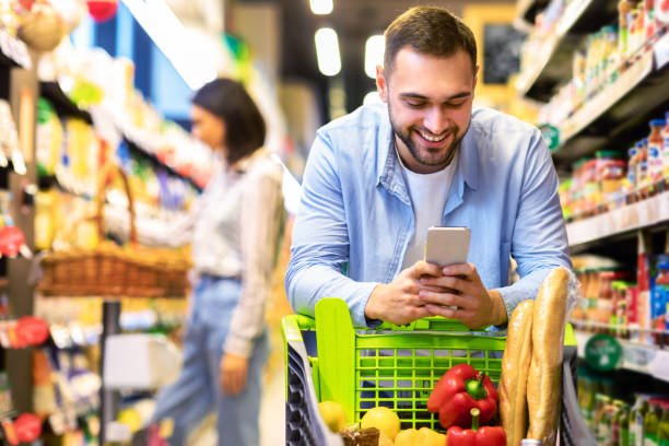 istock Young guy with mobile phone shopping at super market 1305344840