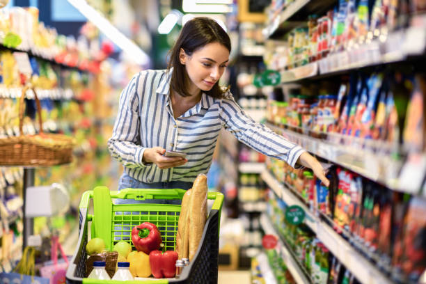 istock Lady holding smartphone standing in store taking products 1305344849