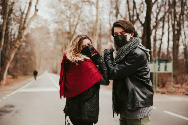 istock couple wearing coronavirus protection mask walking in park 1305345737