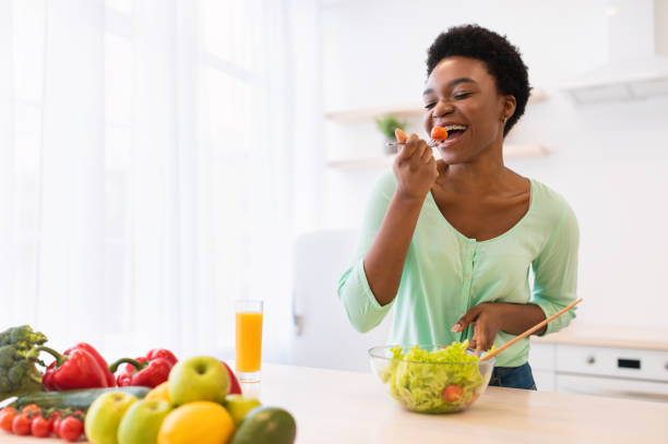 istock Joyful African Lady Enjoying Vegetable Salad Having Dinner In Kitchen 1305346076