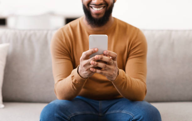 istock Unrecognizable African Man Using Smartphone At Home, Focus On Phone 1305346605